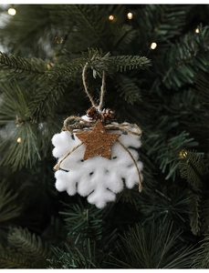 White felt snowflake ornament with pine cone and jute bow on a lit Christmas tree