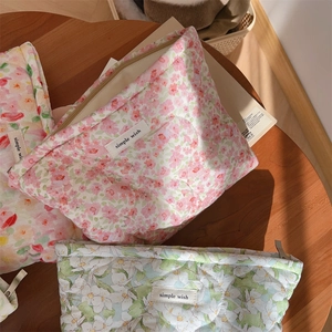 Detailed texture of quilted cotton floral makeup bags on a sunlit wooden desk