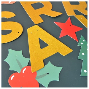 Detail of glittery gold letters and green holly leaves on festive Christmas banner