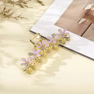 Detail of gold metal hair clip with five purple enamel flowers and sparkling rhinestones