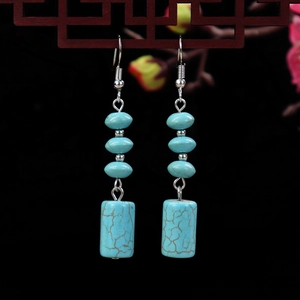 Close-up of vintage turquoise drop earrings hanging on a dark wood lattice screen