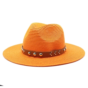 Close-up of orange straw sun hat featuring a brown leather band with silver metal studs
