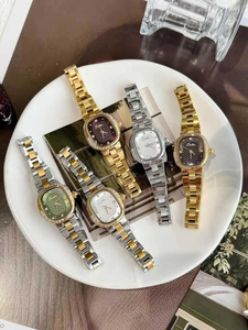 Close-up of five square women's quartz watches with diamond bezels in a ceramic dish