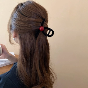 Detail of red bead on black flocked twisted hair claw clip styled on a model's hair