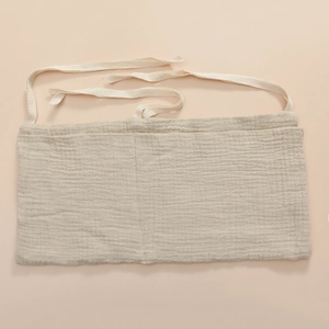Close-up of beige cotton muslin baby bedside organizer with detailed fabric texture