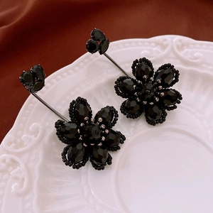 Detailed macro view of black beaded flower earrings resting on a white vintage plate