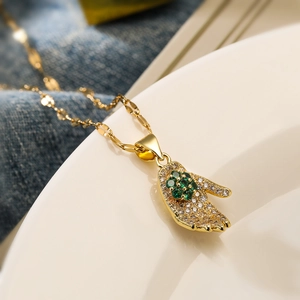 Gold palm pendant necklace with green clover stone and zircon on a white plate