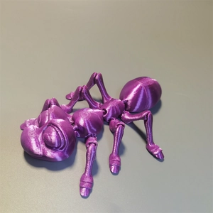 Detailed macro of a purple 3D printed ant toy with movable joints on a grey surface