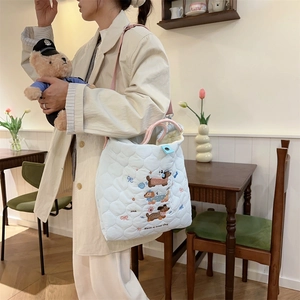 Close-up of white quilted tote bag featuring cute cartoon dog and bow embroidery details