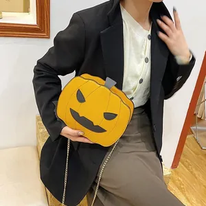 Detail of pumpkin-shaped Halloween crossbody bag with black face and gold chain strap