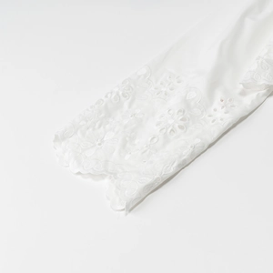 Close-up of white cotton shirt sleeve featuring intricate floral embroidery and eyelet lace