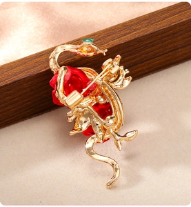 Detailed close-up of golden snake and red rose brooch with high-quality enamel finish