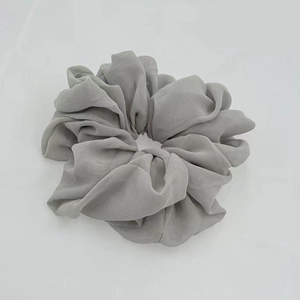 Close-up of a grey chiffon elastic hair scrunchie with soft fabric texture on white background