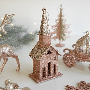 Glittery rose gold Christmas reindeer and house tree ornaments set in festive warm light