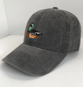 Detail of pixel art mallard embroidery on washed charcoal cotton baseball cap texture