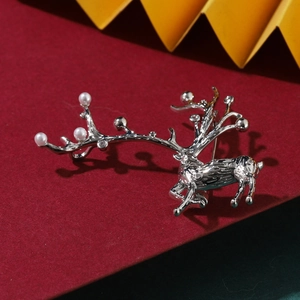 Broche renne argentée avec perles blanches et strass brillants sur fond festif rouge