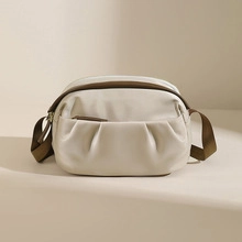 Detail of beige soft leather crossbody bag with front zipper and brown strap
