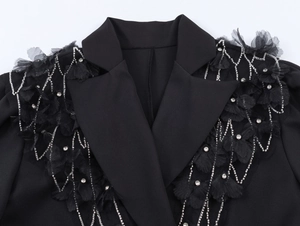 Détail de la robe blazer noire avec fleurs perlées et franges en strass argentés