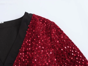 Dettaglio del tessuto con paillettes rosse, colletto nero e etichetta taglia S