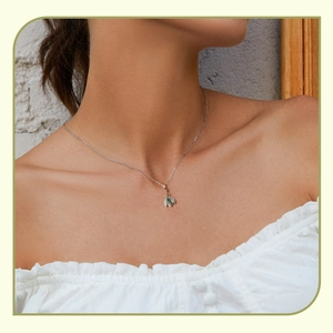 Detail of insect pendant necklace with green stone on model's neckline