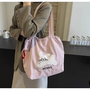 Detailed shot of pink canvas tote bag featuring a cute plush bunny and embroidery