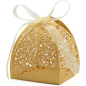 Close-up of golden laser-cut wedding candy box with intricate rose patterns and ribbon