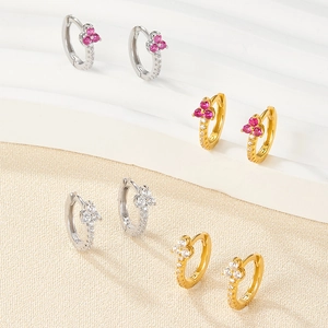 Dettaglio di orecchini huggie in argento S925 con zirconi e accenti di trifoglio