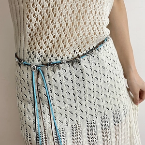 Detail of bohemian braided suede waist chain with silver charms on a white dress