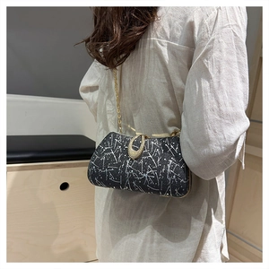 Detail of black evening clutch with gold chain strap and unique oval clasp closure