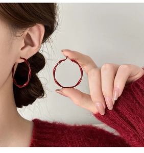 Close-up of vintage dark red twisted hoop earrings worn with a cozy knit sweater