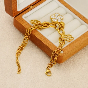 Bracelet doré à double chaîne avec fleurs serties de zircones sur fond de velours blanc