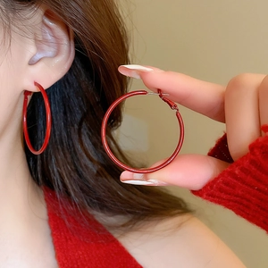 Close-up of large red enamel hoop earrings in minimalist style worn by model
