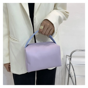 Detail of lavender rectangular handbag with top handle shown on a model's arm