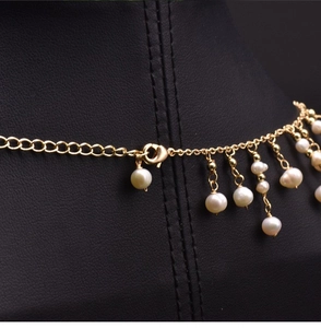 Detailed shot of gold chain necklace with freshwater pearl tassels on a black bust