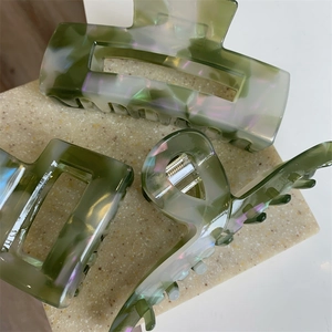 Green marble texture acetate hair claw clips for women set on a stone display