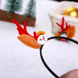 Dettaglio di un cerchietto natalizio con corna di renna in peluche e un Babbo Natale
