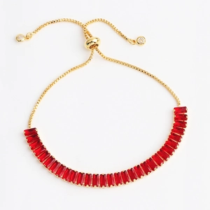 Detail of gold adjustable slider bracelet featuring vibrant red rectangular gemstones