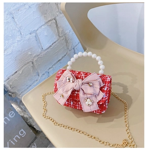 Close-up of red tweed girl bag with pink bow, pearl handle and gold chain detail