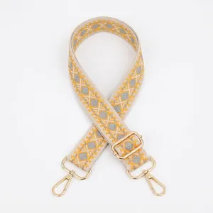 Dettaglio della tracolla jacquard geometrica con moschettoni e fibbie in metallo dorato
