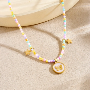 Collier de perles colorées avec pendentif papillon doré et petites étoiles sur fond beige