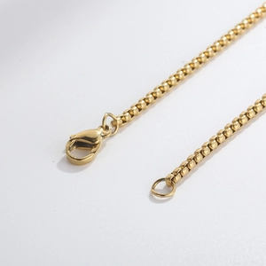 Detailed macro view of a gold square box chain featuring a secure lobster clasp closure