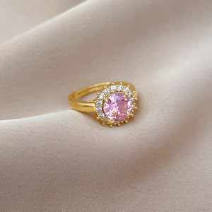 Détail d'une bague ajustable dorée avec zircon rose rond et entourage de cristaux