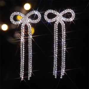 Macro shot of silver bow earrings featuring sparkling rhinestone fringe and tassels