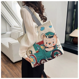 Detailed shot of a beige canvas tote bag with colorful bear driving a train print