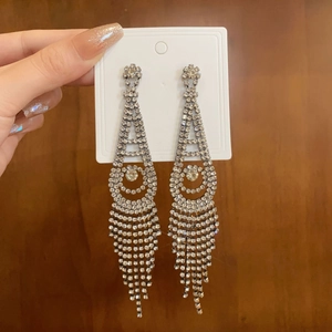 Detail of silver long tassel earrings with sparkling rhinestones in a floral fringe design