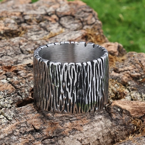 Detail of wide stainless steel ring with bark texture placed on natural tree bark