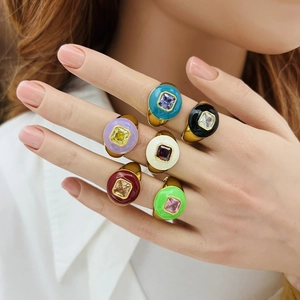 Close-up of a hand wearing multi-colored enamel and zircon gold rings in diverse styles
