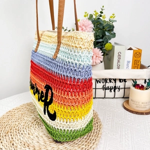 Detail of colorful striped woven beach tote with summer embroidery and brown leather handles
