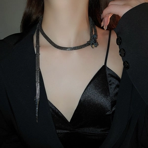 Macro detail of snake-shaped fringe necklace with rhinestones on dark metal mesh