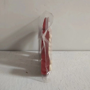 Side view of red wooden gingerbread man table decor in protective plastic packaging